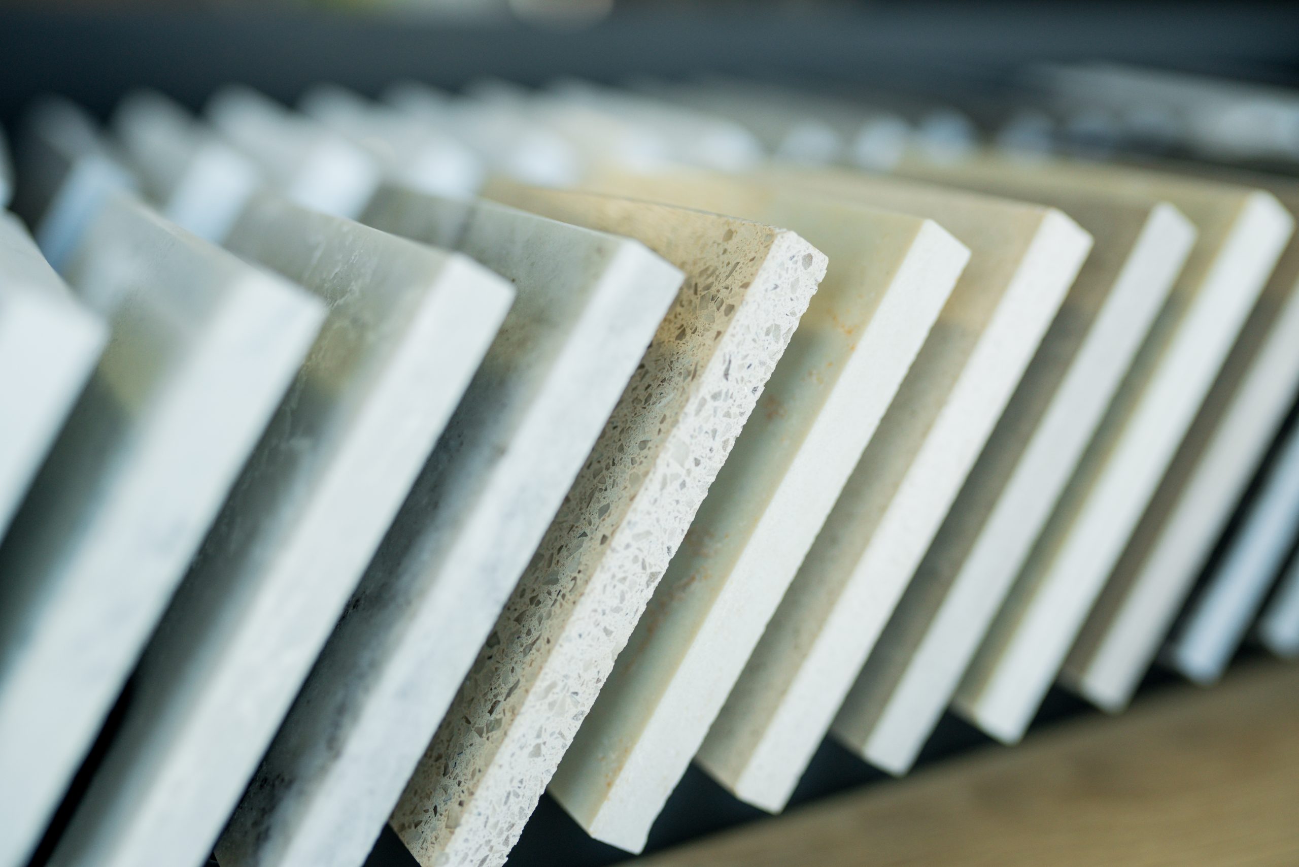 Hands holding marble, quartz, and granite countertop samples in a kitchen design showroom