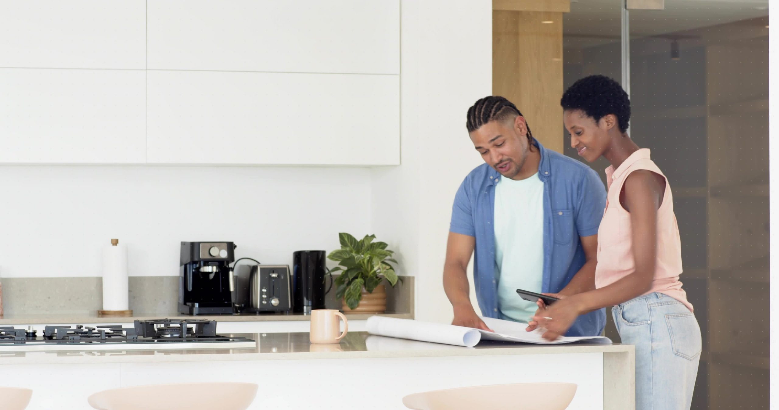 Bucks County homeowners reviewing kitchen renovation plans on blueprints and a tablet at a modern kitchen island
