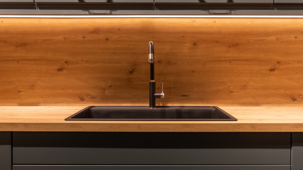 Installer sealing the sink cutout of a maple butcher block countertop in a kitchen