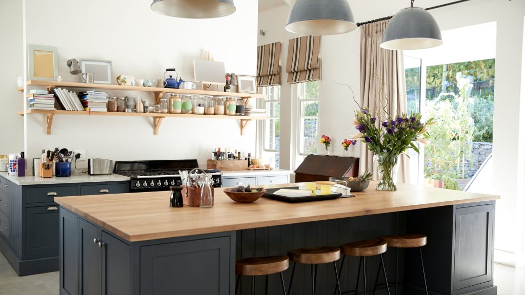 Three open metal pendant shades hanging above a kitchen island, each casting a defined pool of light on the countertop
