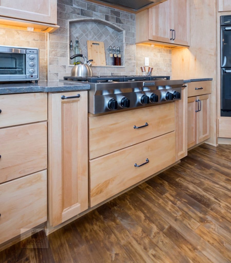 Close view of natural maple kitchen cabinet doors and a four-drawer bank, showing the narrow shadow line of a full overlay arrangement on a face-frame cabinet