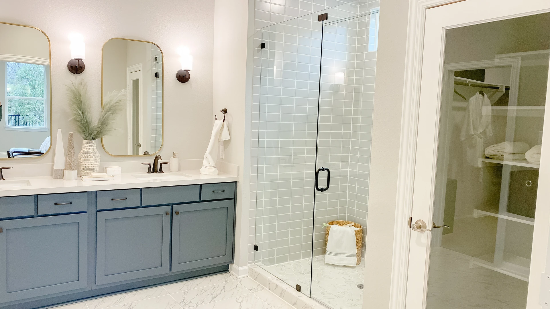 Bathroom with a blue double vanity, two mirrors and a glass-enclosed shower