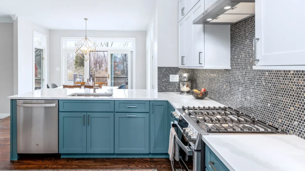 Teal kitchen peninsula with a white counter, a sink and a stainless steel dishwasher beside a stainless steel range, with a mosaic backsplash and a wall plate above the counter